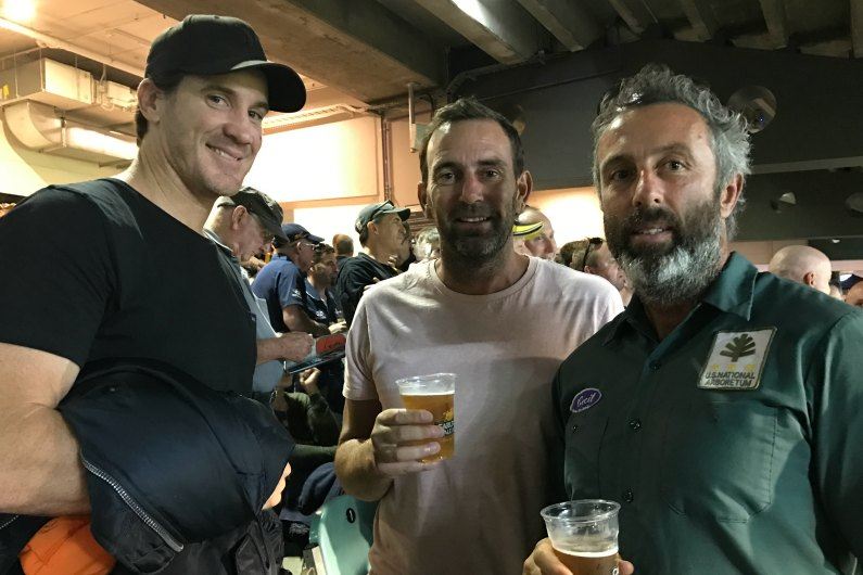 Simon Fletcher, Daniel Healy and Justin Peckett standing in a football stadium with drinks