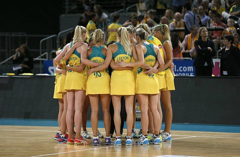 The Australian national netball team in a team huddle on court